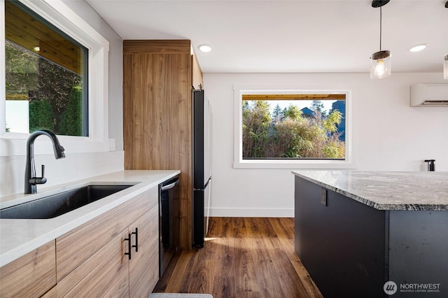 kitchen featuring a sink, dark wood-style floors, dishwashing machine, baseboards, and hanging light fixtures