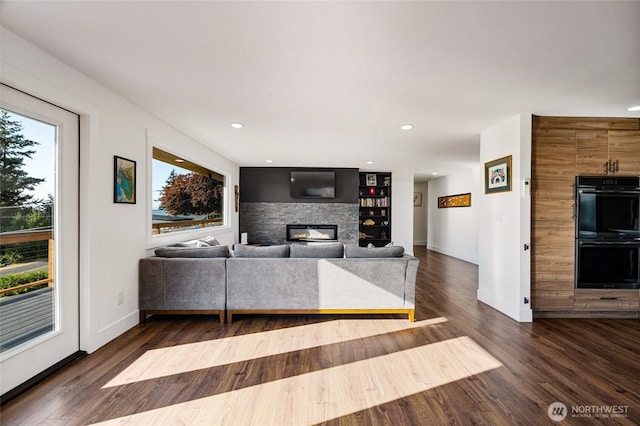 unfurnished living room with wood finished floors, recessed lighting, a fireplace, and baseboards