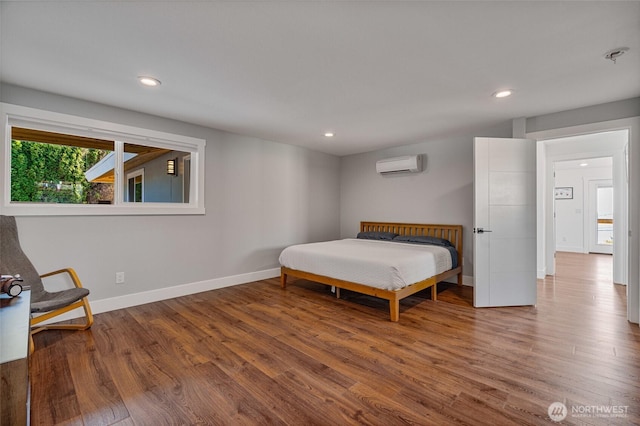 bedroom with recessed lighting, wood finished floors, baseboards, and a wall mounted air conditioner