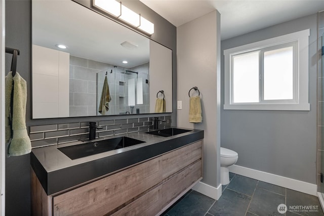 bathroom featuring double vanity, baseboards, a stall shower, and a sink