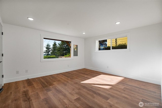 spare room featuring electric panel, wood finished floors, recessed lighting, and baseboards