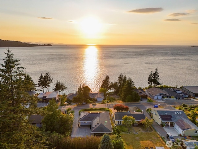 aerial view at dusk featuring a water view