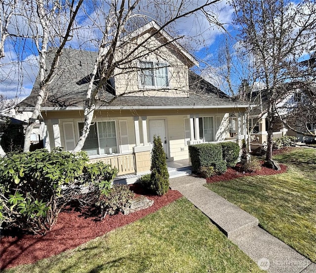 view of front of house featuring roof with shingles, covered porch, and a front yard