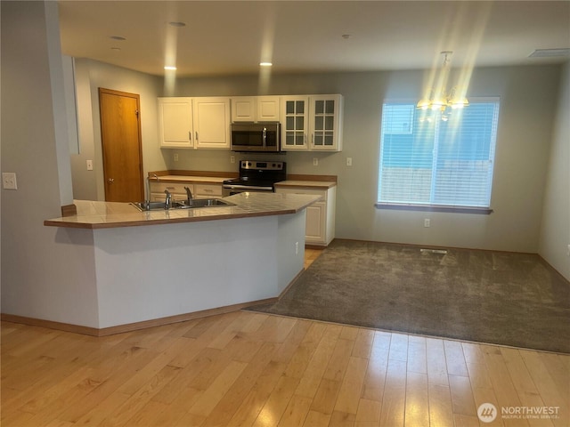 kitchen featuring white cabinets, glass insert cabinets, appliances with stainless steel finishes, and a sink