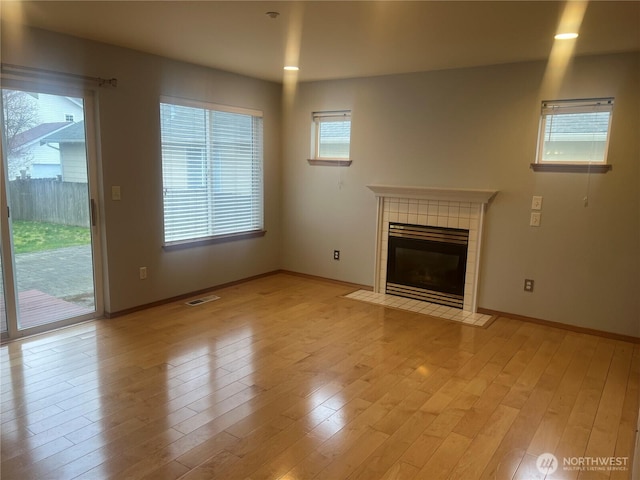 unfurnished living room featuring visible vents, baseboards, light wood-style flooring, and a fireplace