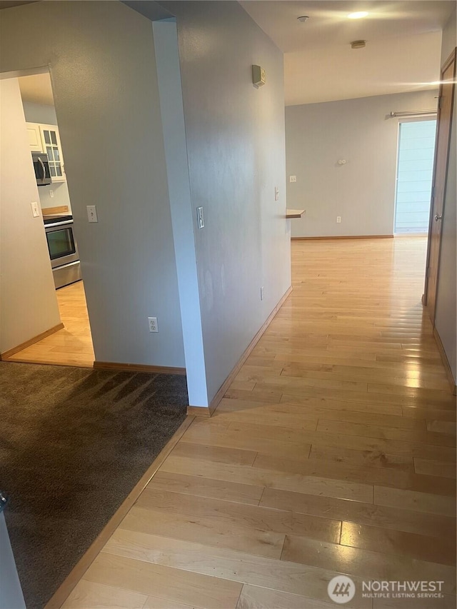 corridor with light wood-style floors and baseboards