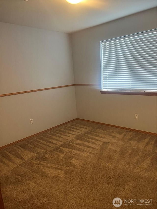 carpeted spare room featuring baseboards