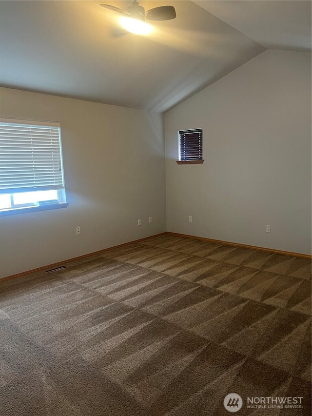 carpeted empty room featuring visible vents, baseboards, a ceiling fan, and vaulted ceiling