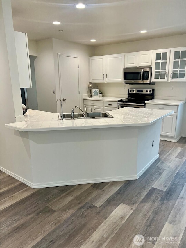 kitchen with tile countertops, a sink, appliances with stainless steel finishes, and white cabinets