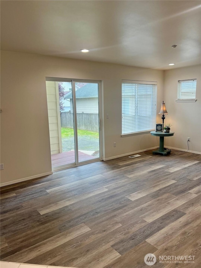 spare room with baseboards, recessed lighting, wood finished floors, and a wealth of natural light