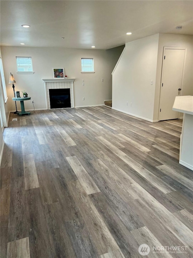 unfurnished living room featuring recessed lighting, a tiled fireplace, and wood finished floors
