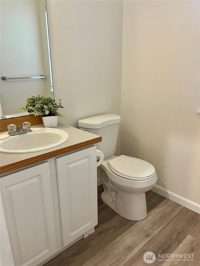bathroom featuring vanity, baseboards, wood finished floors, and toilet