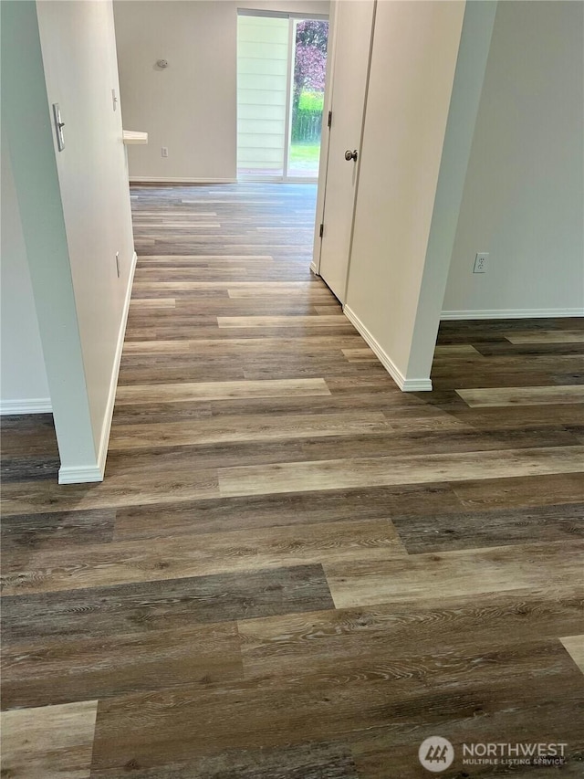 corridor featuring baseboards and wood finished floors