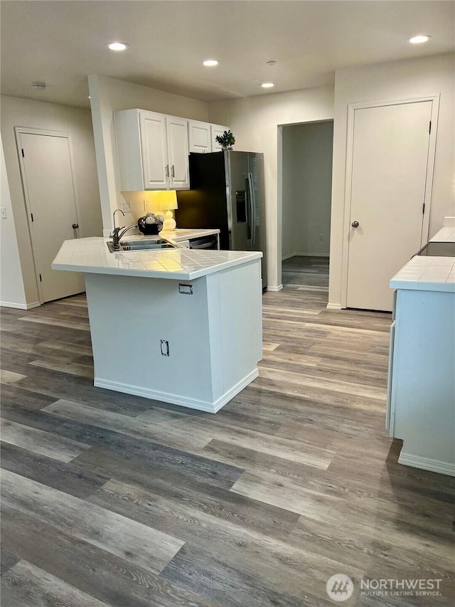 kitchen featuring tile counters, a sink, a peninsula, and wood finished floors