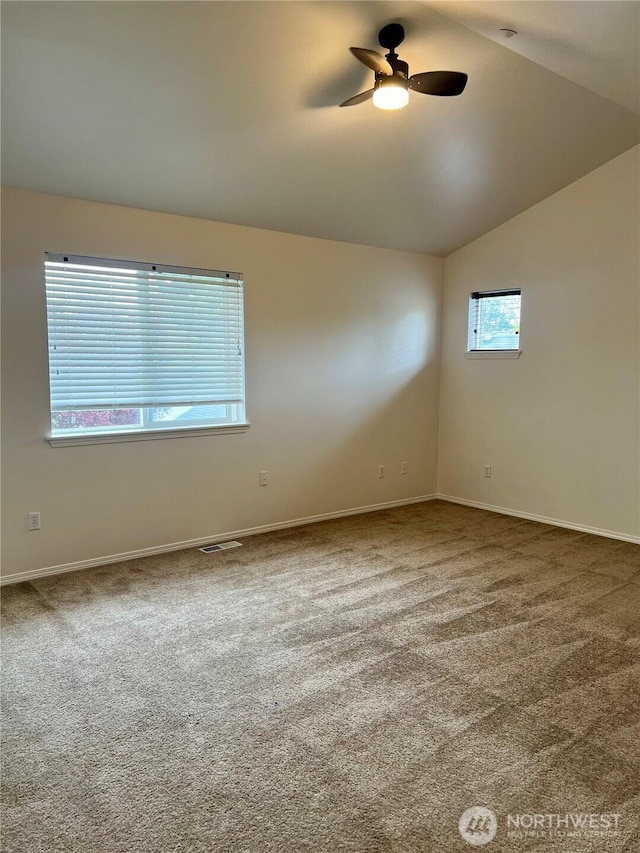 carpeted empty room featuring baseboards, ceiling fan, lofted ceiling, and visible vents