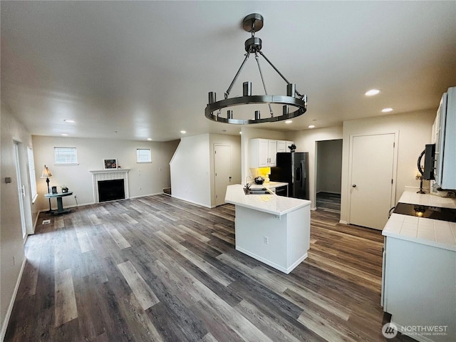 kitchen with light countertops, black appliances, dark wood-style flooring, and open floor plan