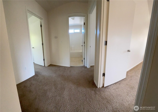 hallway featuring baseboards and carpet
