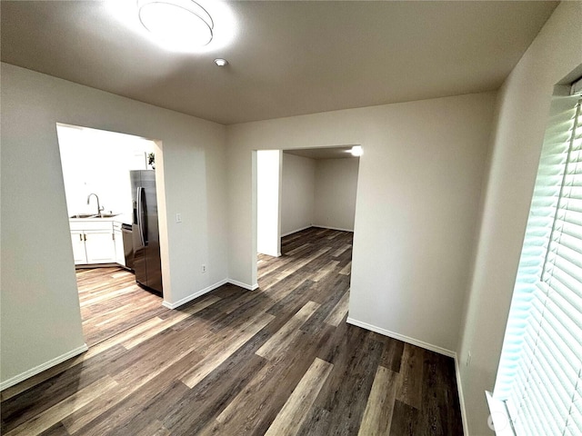 empty room with baseboards, dark wood-style floors, and a sink
