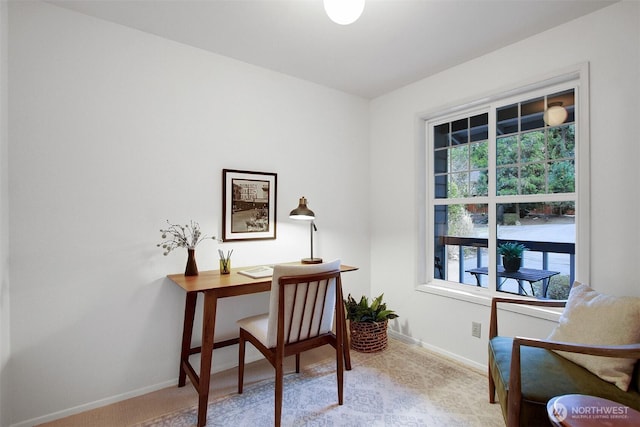 office area featuring plenty of natural light, baseboards, and light carpet