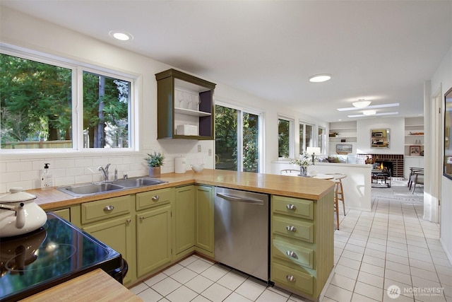 kitchen with stainless steel dishwasher, a peninsula, a sink, and green cabinetry