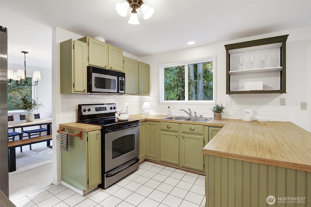 kitchen featuring tasteful backsplash, a sink, appliances with stainless steel finishes, wood counters, and green cabinetry