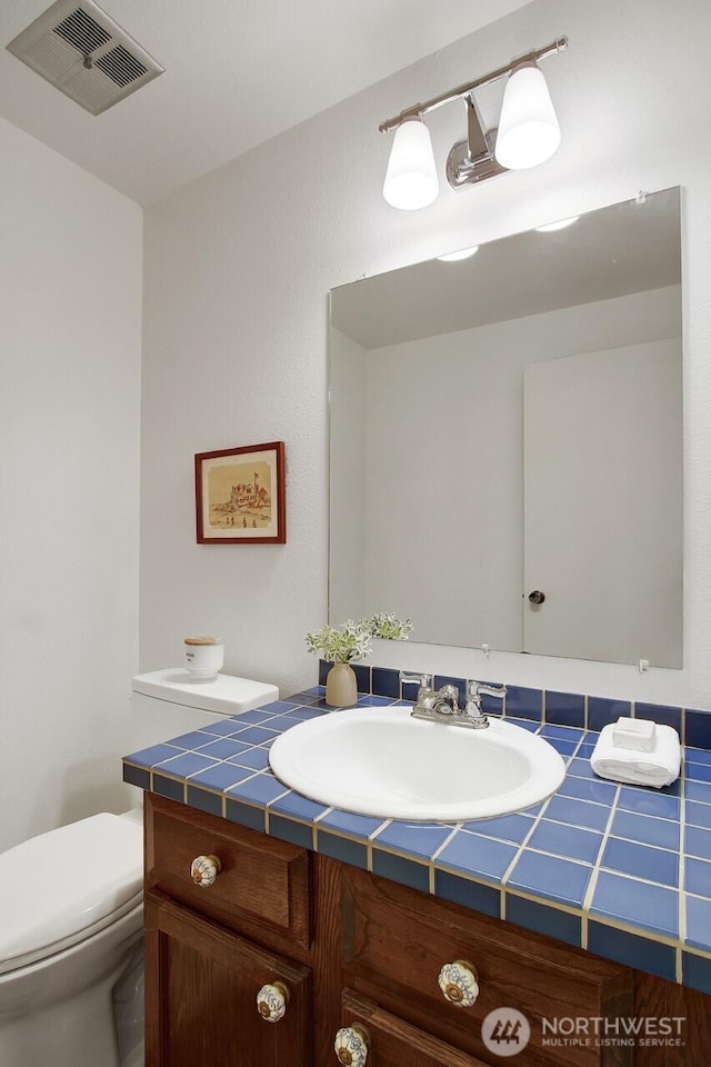 half bathroom with visible vents, toilet, and vanity