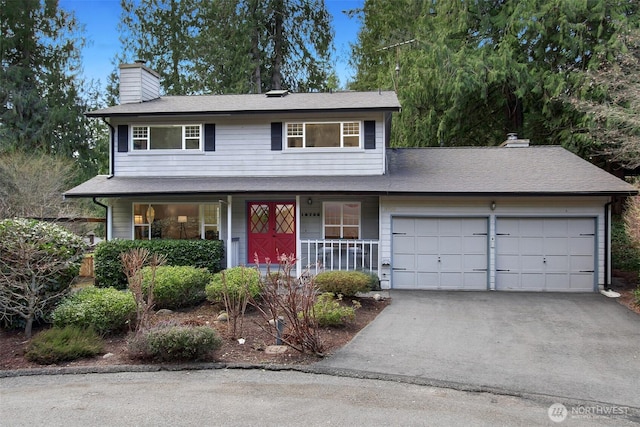 traditional-style home featuring driveway, an attached garage, covered porch, and a chimney