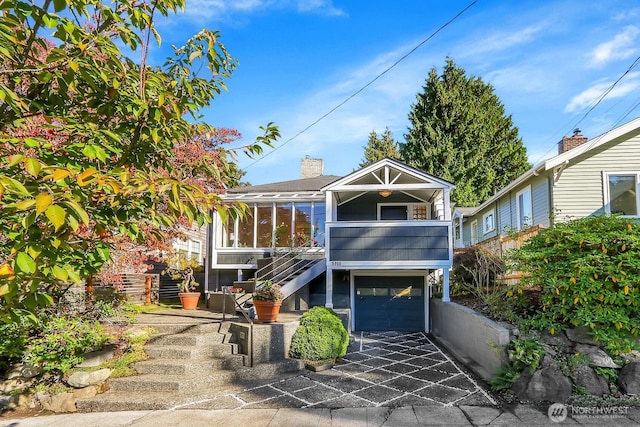 view of front of house with stairway, a garage, and a sunroom