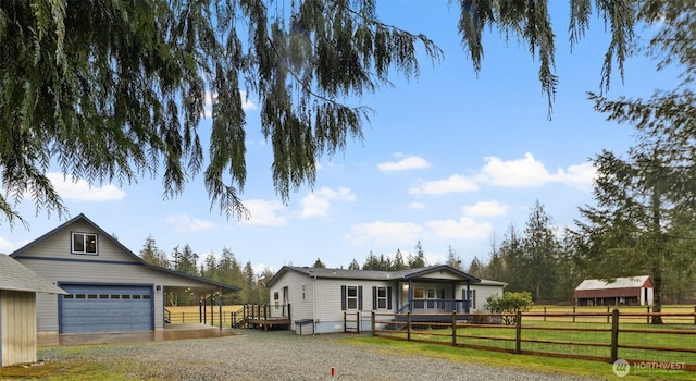 view of front of property with a front lawn, fence, a wooden deck, a garage, and an outbuilding