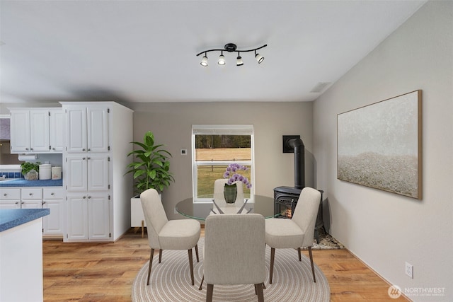 dining room with light wood-type flooring and a wood stove