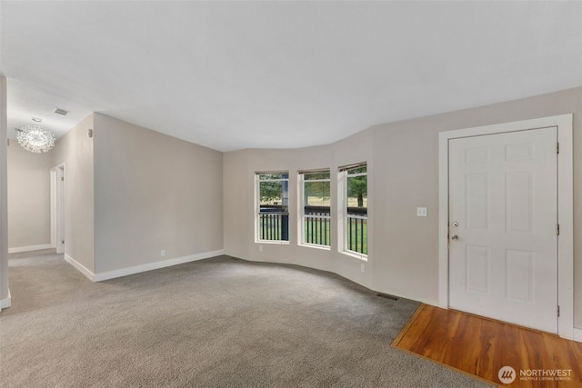 interior space with baseboards, carpet floors, and a chandelier