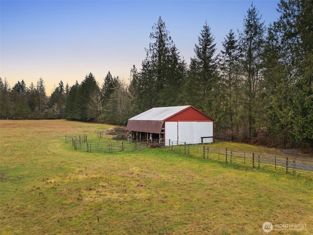 view of yard with a view of trees, an outbuilding, a rural view, and an exterior structure