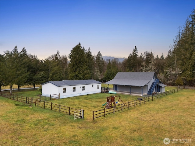 view of front of property featuring a front lawn, an outbuilding, fence, and a pole building