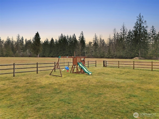 exterior space with a rural view, a yard, fence, and a playground