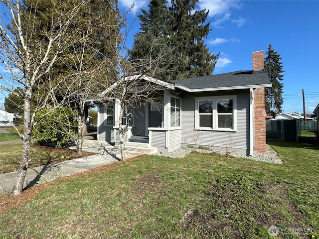 bungalow-style home featuring a shingled roof, a chimney, and a front lawn