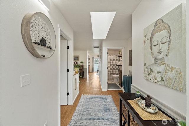 hallway featuring a skylight and wood finished floors