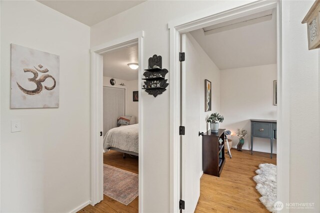 corridor with baseboards and wood finished floors