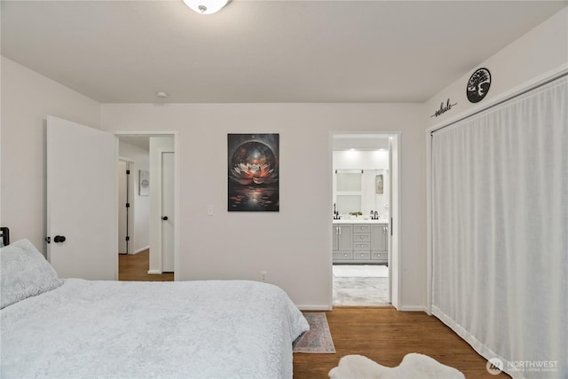 bedroom with a sink, baseboards, ensuite bath, and wood finished floors