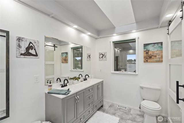 bathroom featuring double vanity, toilet, baseboards, and a sink