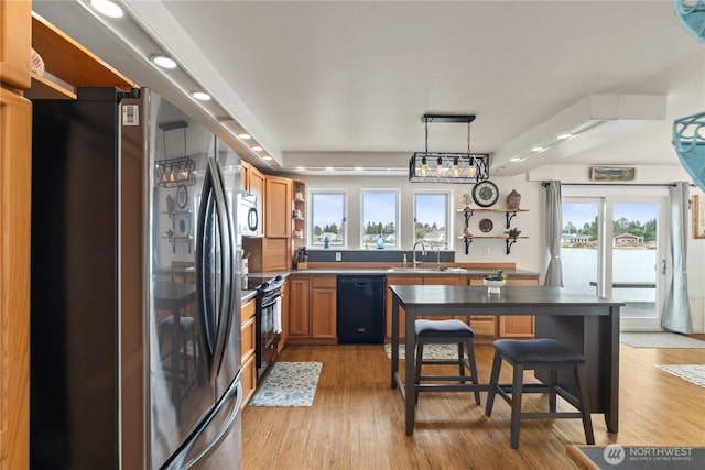 kitchen with black appliances, open shelves, a sink, light wood finished floors, and hanging light fixtures