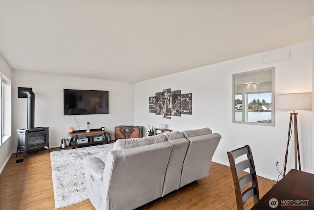 living room featuring a wood stove, baseboards, and wood finished floors