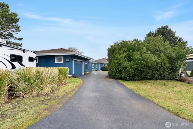 view of front of house with aphalt driveway, a front lawn, and a garage