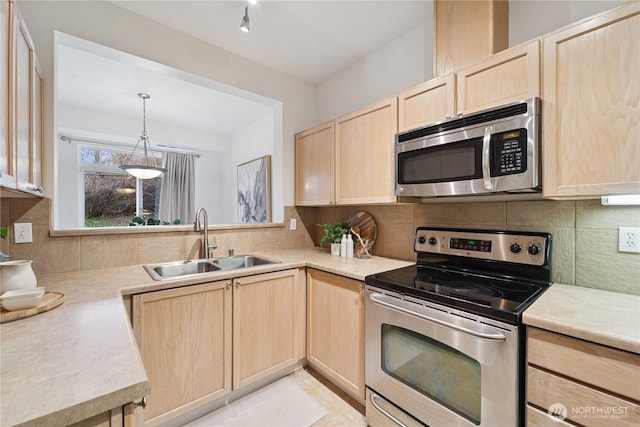 kitchen featuring a sink, backsplash, appliances with stainless steel finishes, and light brown cabinetry