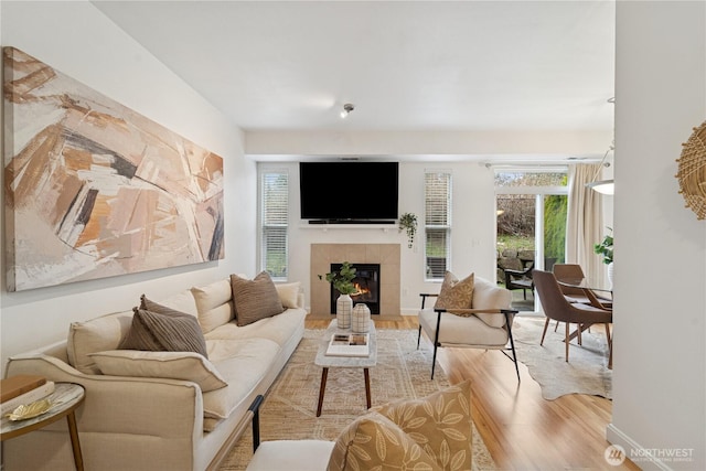 living area featuring a tiled fireplace, wood finished floors, and baseboards