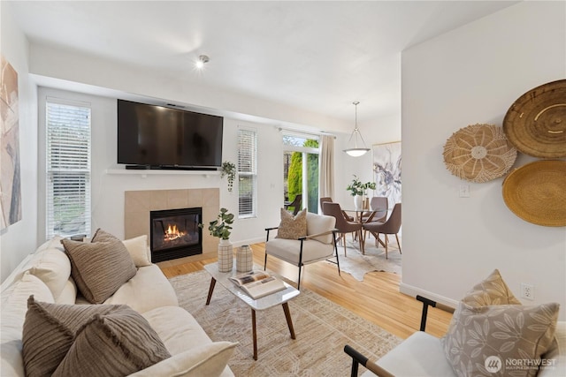 living area with a wealth of natural light, light wood-style flooring, a fireplace, and baseboards