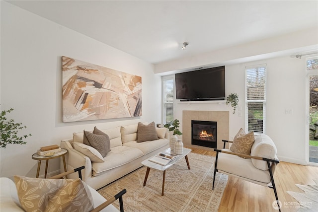 living area featuring a fireplace, wood finished floors, and baseboards