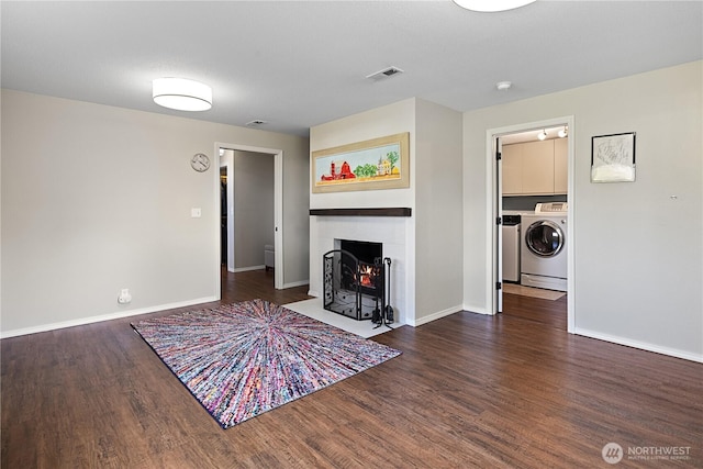 unfurnished living room with a fireplace with flush hearth, visible vents, baseboards, and wood finished floors