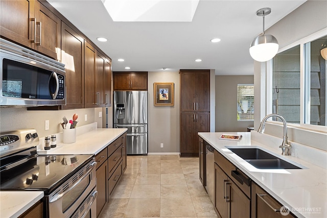 kitchen with recessed lighting, a sink, dark brown cabinets, appliances with stainless steel finishes, and pendant lighting