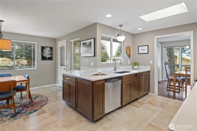 kitchen featuring a wealth of natural light, a sink, stainless steel dishwasher, a skylight, and light countertops