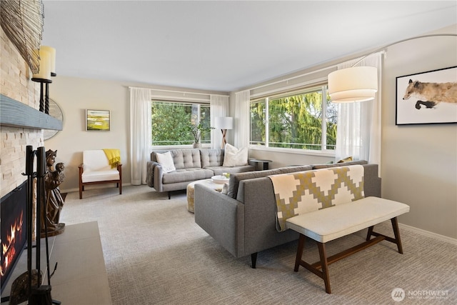 living area with a healthy amount of sunlight, a large fireplace, baseboards, and carpet floors